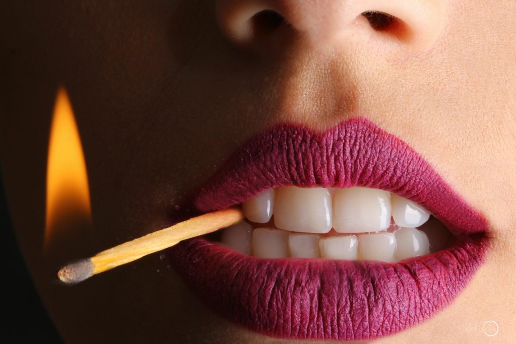 Imagen de la boca de una chica sujetando una cerilla con los dientes para un artículo de Vivir en Astrológico.