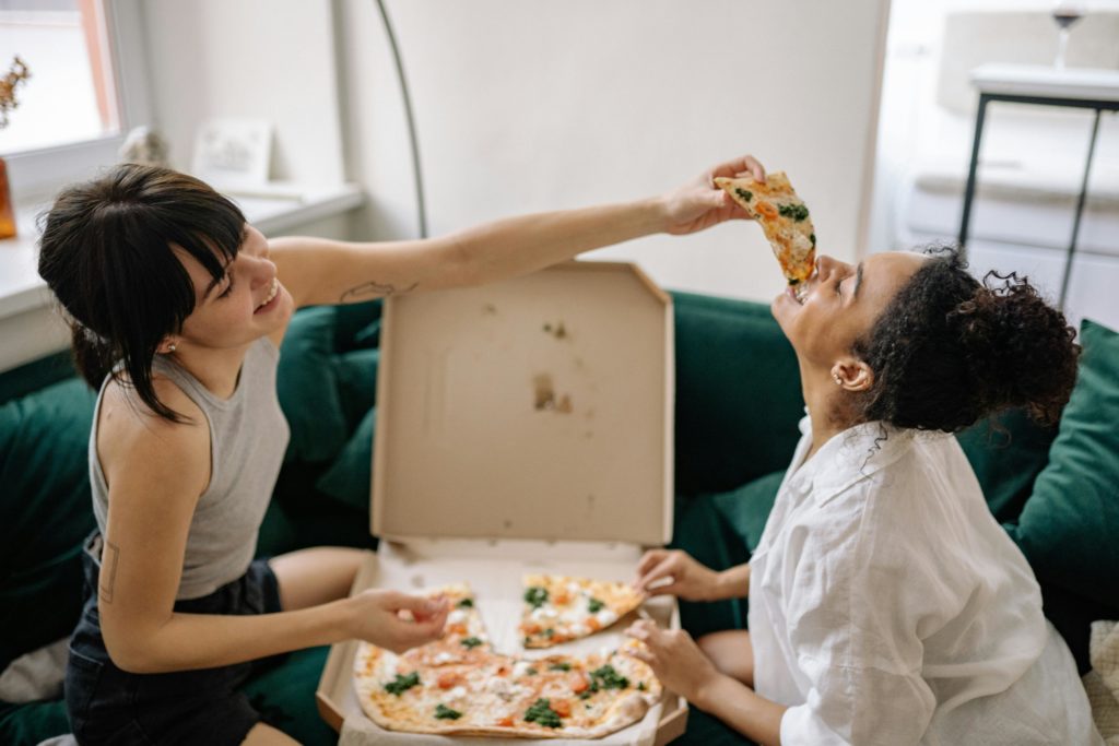 Foto de dos amigas comiendo pizza para un artículo de Vivir en Astrológico.